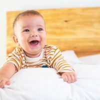 A closeup shot of a cute smiling baby on a bed